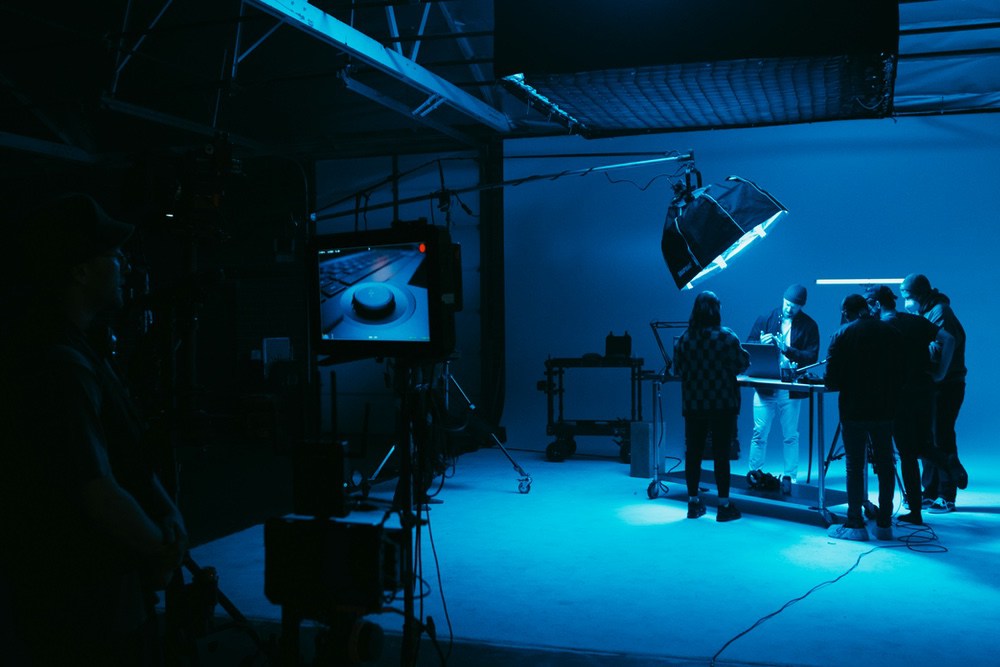 Wide view of a film studio set with crew working under blue light